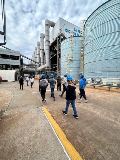 Students in blue hats walking around the plant.